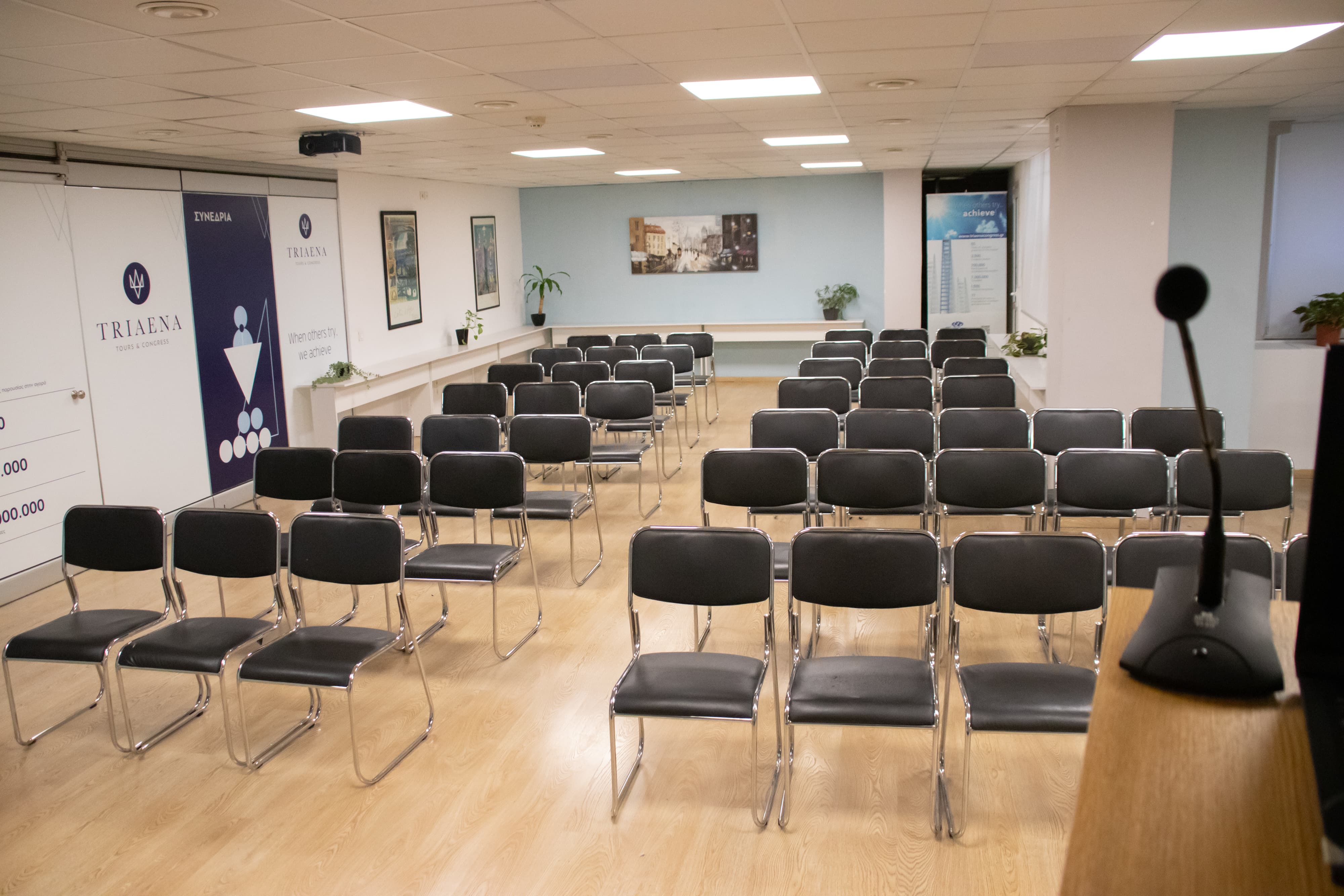 Event hall with rows of black chairs and a microphone stand in the foreground, ideal for private gatherings, speeches, or community events