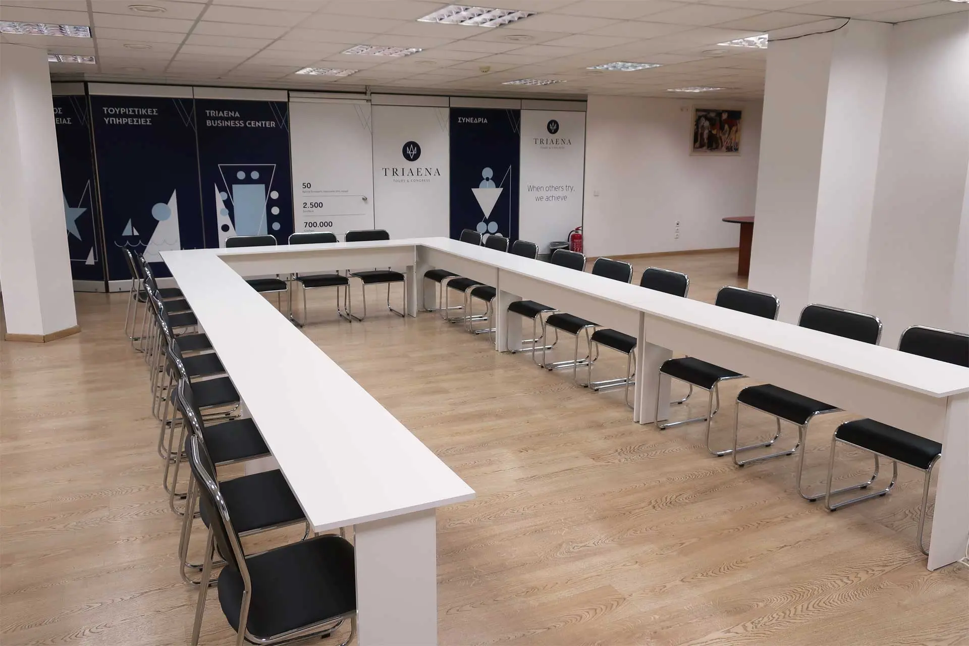 Meeting room with u-shaped table configuration and black chairs, ideal for board meetings or workshops.